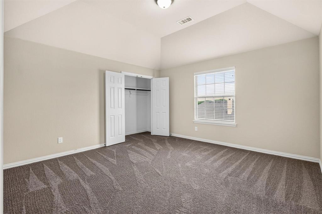 Vaulted ceiling, neutral wall tones, wall-to-wall carpeting, window with muntins, and reach-in closet with double-panel doors
