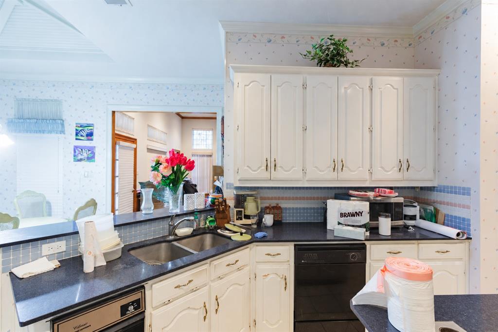 Kitchen featuring white cabinetry, dark countertops, a double-basin stainless steel sink with a pull-down faucet, and a black built-in dishwasher