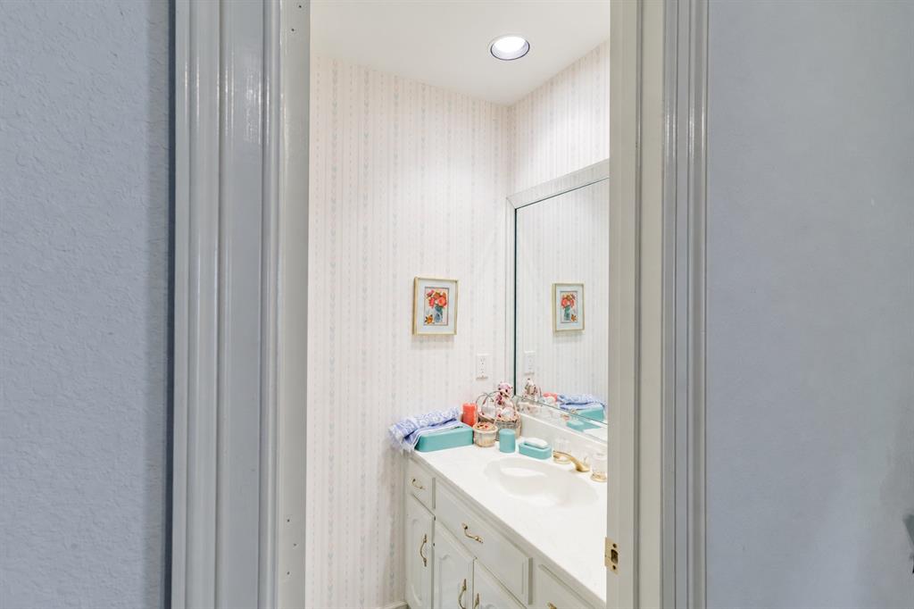 Built-in vanity featuring a seamless countertop with an integrated basin, white cabinetry, a large wall-mounted mirror, and recessed ceiling lighting