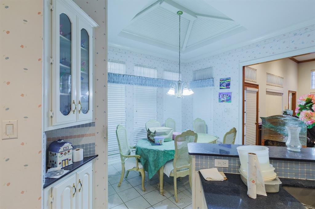 Dining area featuring a tray ceiling, tile flooring, built-in cabinetry with glass-front uppers, and solid-surface countertops