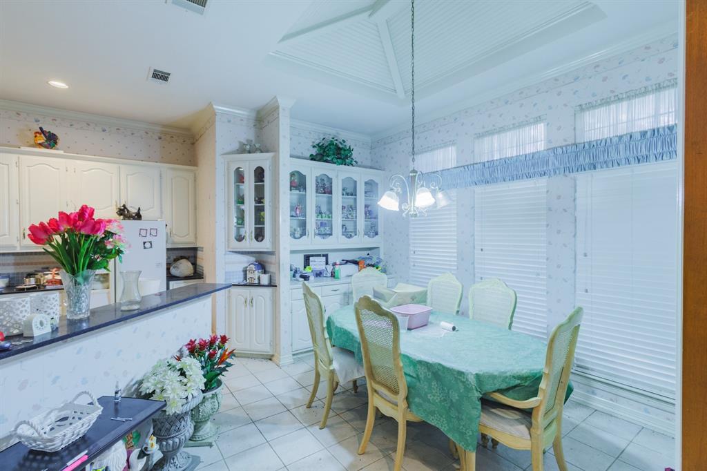 Kitchen featuring white cabinetry, built-in display hutch, stone-finish countertops, tile flooring, and a tray ceiling