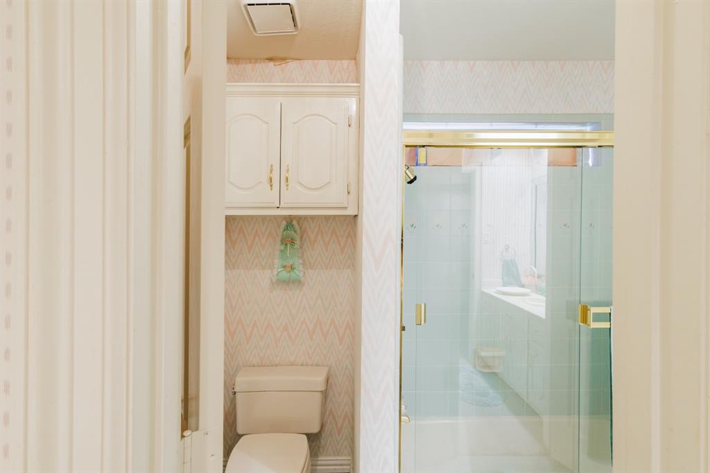 Bathroom featuring an enclosed shower with glass sliding doors, wall-mounted cabinetry, and a dual-flush toilet