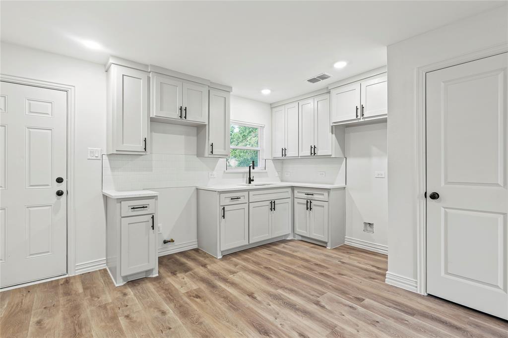 Kitchen featuring a sink, light wood finished floors, backsplash, recessed lighting, and baseboards