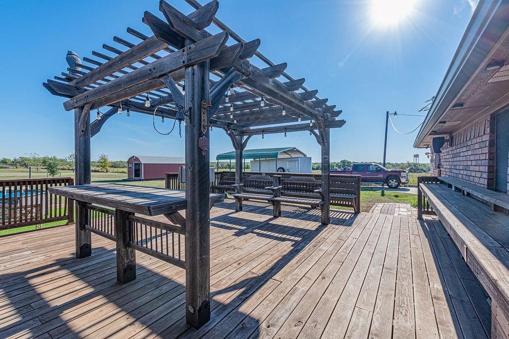Expansive wood-plank deck featuring a built-in pergola and integrated wooden bench seating