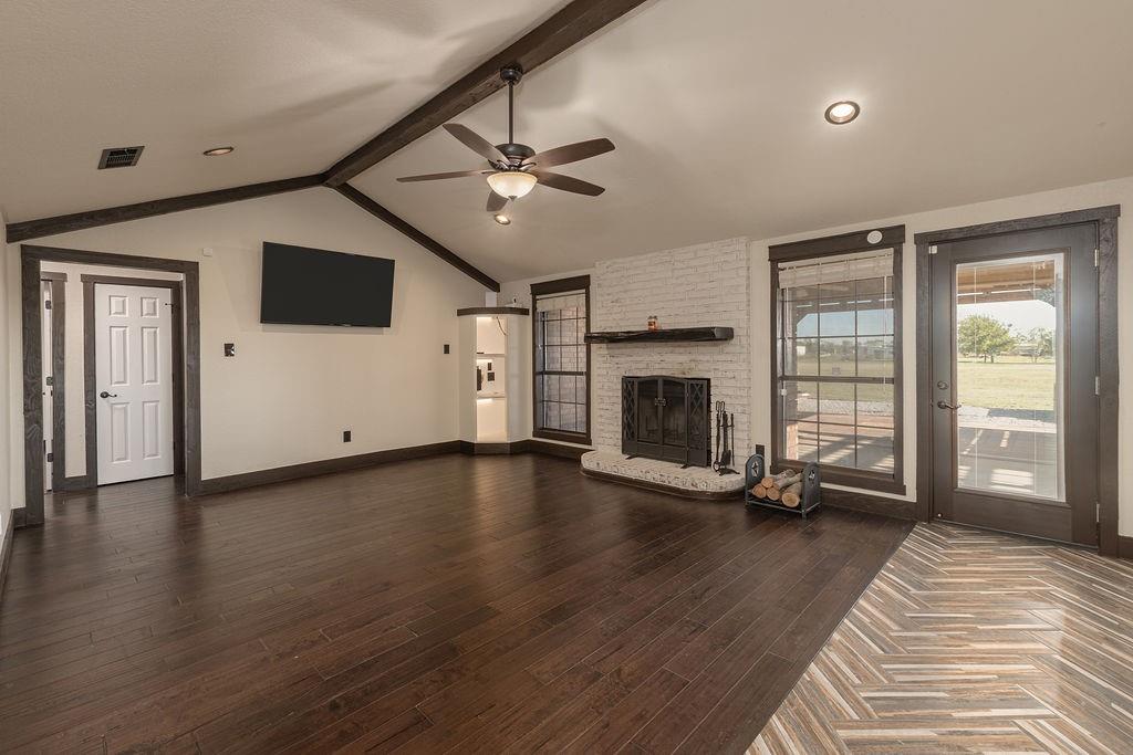 Vaulted ceiling with exposed wood beams and a brick fireplace