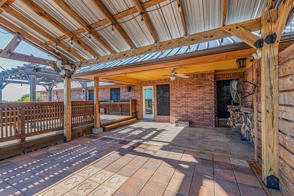 Covered patio featuring a metal roof, wood-frame pergola, patterned concrete pavers, and built-in bar counter