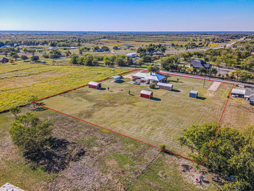 Expansive acreage featuring a main residence, multiple detached storage structures, and open green space