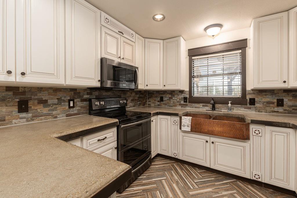 Kitchen featuring a hammered copper apron-front sink, an electric range and a microwave