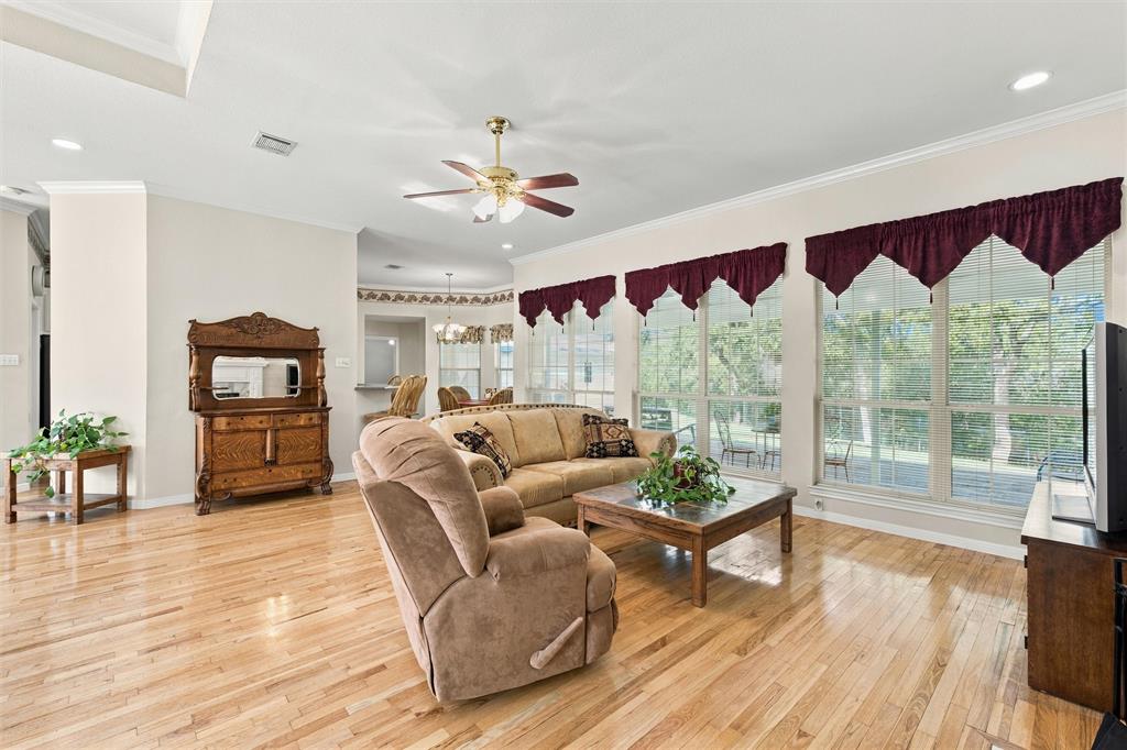Open-concept interior featuring light wood-finish flooring, recessed lighting, crown molding, and a central ceiling fan