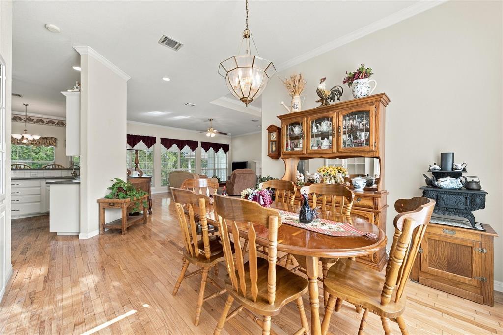 Dining space featuring wood-finish flooring, crown molding, and a geometric multi-light pendant fixture