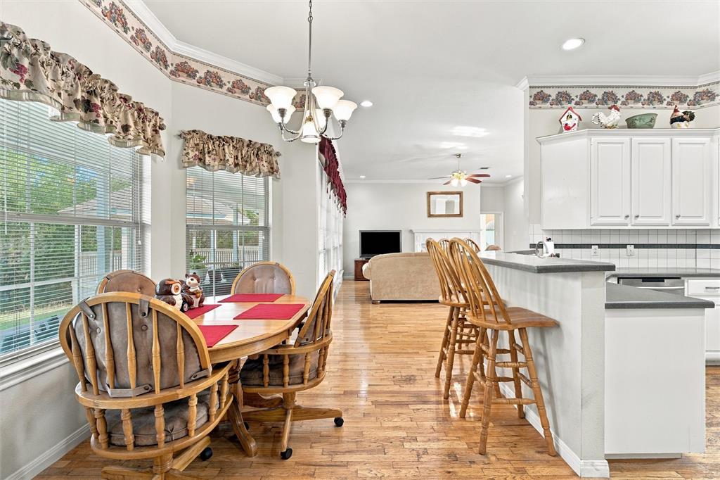 Kitchen featuring white cabinetry, a breakfast bar with stone-finish countertops, wood-finish flooring, and a multi-light chandelier