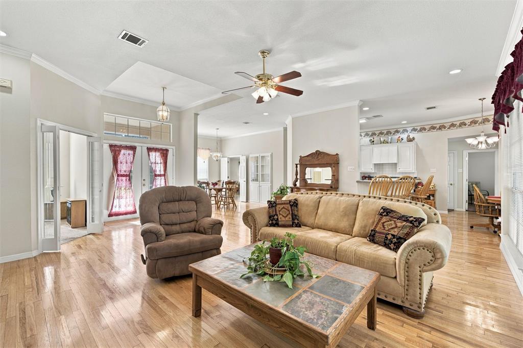 Open-concept living space featuring wood-finish flooring, recessed lighting, double-door entryway with transom window, and ceiling fans