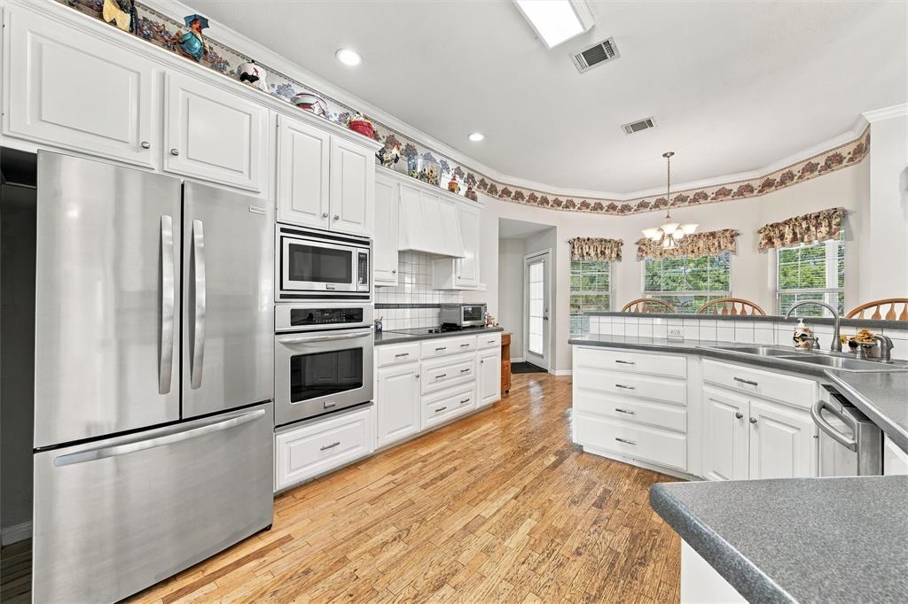 Kitchen featuring white cabinetry, wood-finish flooring, stainless steel appliances, a built-in wall oven and microwave, and recessed lighting