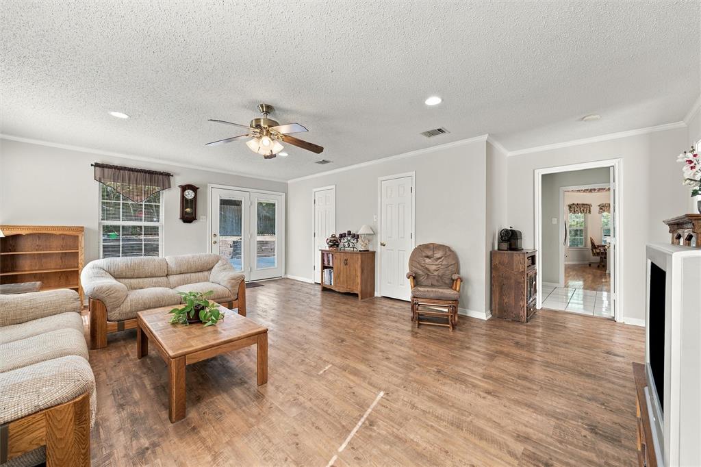 Living area featuring wood-finish flooring, recessed lighting, a ceiling fan with integrated light fixture, and double glass-paned doors