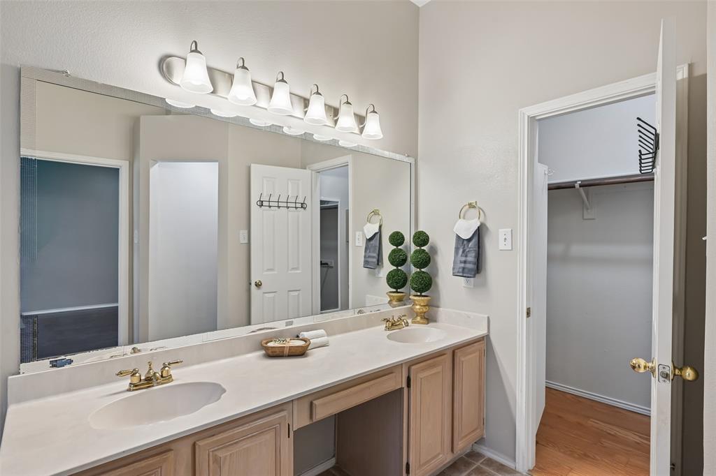 Double vanity with integrated sinks, neutral solid-surface countertop, six-light fixture, and built-in cabinetry