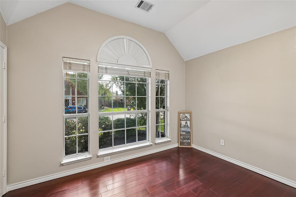 Vaulted ceilings, wood-finish flooring, and a large multi-pane window assembly featuring an arched transom top