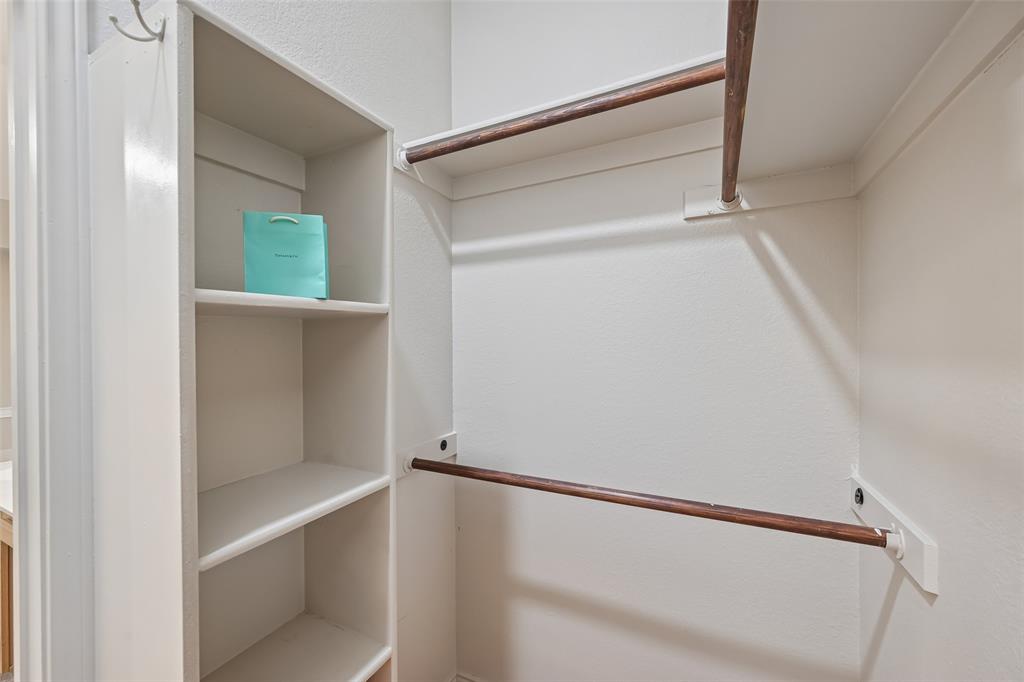 Storage area featuring built-in vertical shelving and dual-tier wooden hanging rods