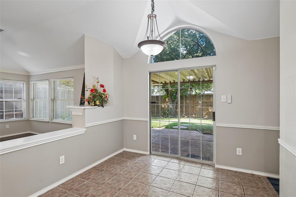 Vaulted ceiling featuring an arched transom window, ceramic tile flooring, and a multi-light metal chandelier