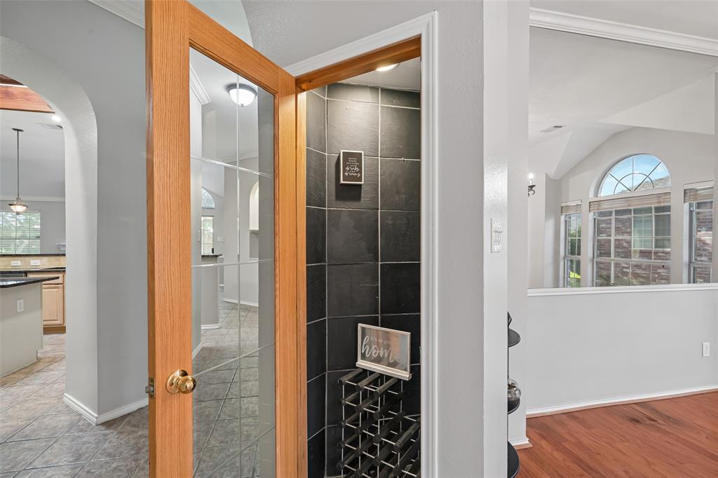 Wine closet, glass-paneled wood door entry, dark tile accent wall, and recessed lighting