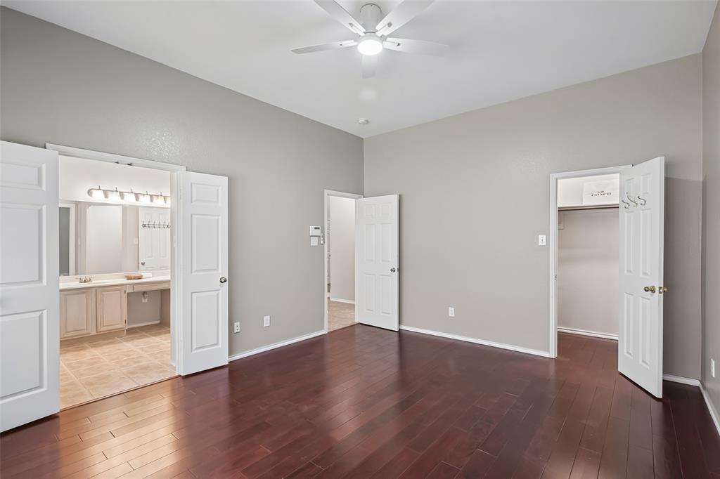 Room featuring wood-finish flooring, vaulted ceilings, a ceiling fan, six-panel interior doors, and a walk-in closet