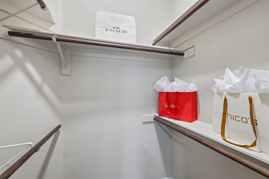 Walk-in closet featuring multi-level wood shelving and integrated hanging rods