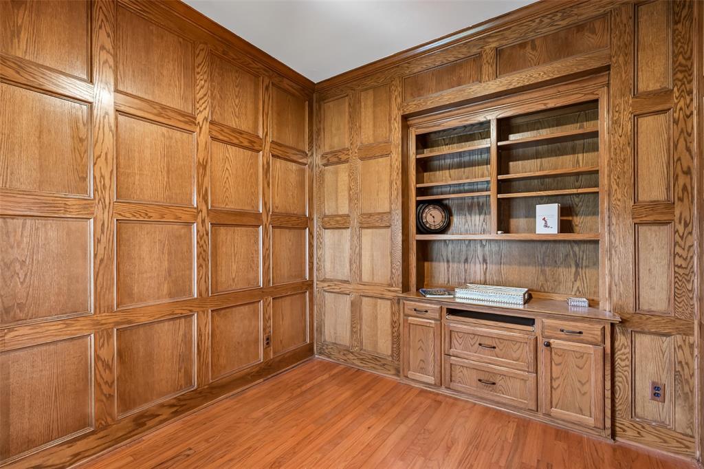 Custom wood-paneled walls, built-in floor-to-ceiling shelving, integrated cabinetry with drawers, and wood-finish flooring