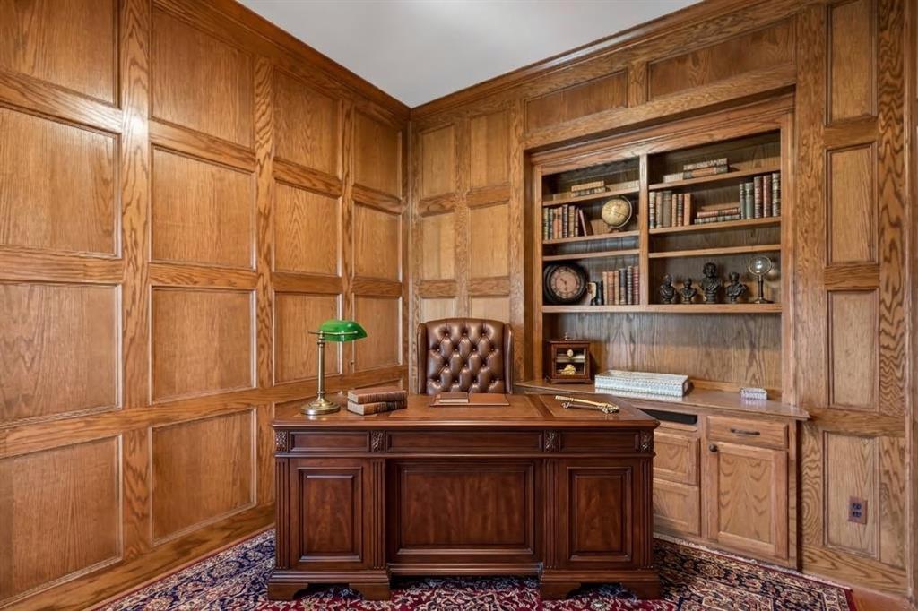 Wood-paneled walls with decorative wainscoting and custom built-in cabinetry featuring integrated shelving and lower storage drawers