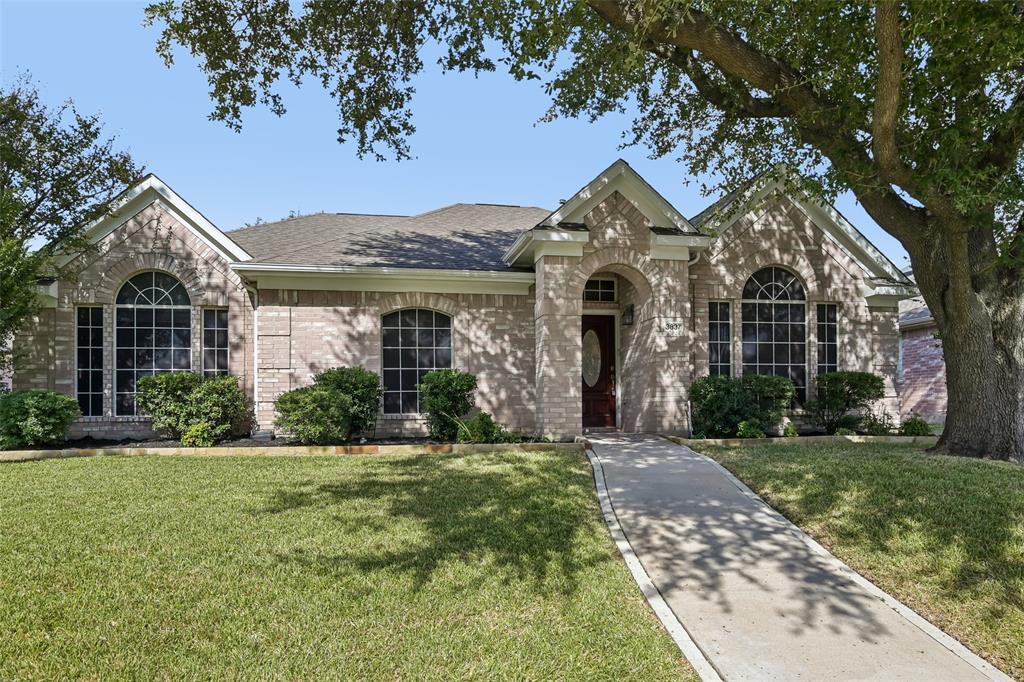 Brick exterior featuring an arched entryway, gabled rooflines, decorative transom windows, and a concrete walkway