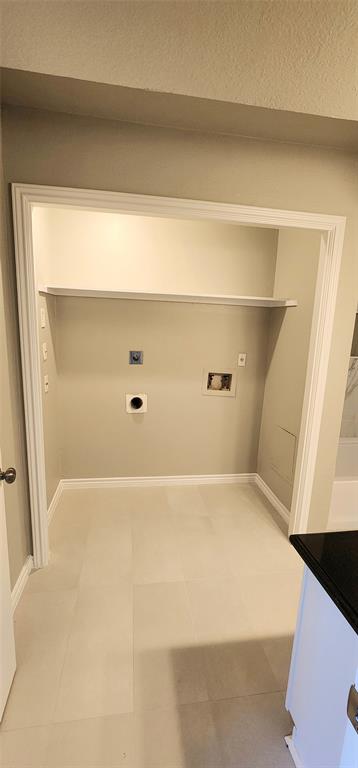 Utility area featuring large-format tile flooring, a recessed nook, and a built-in overhead shelf
