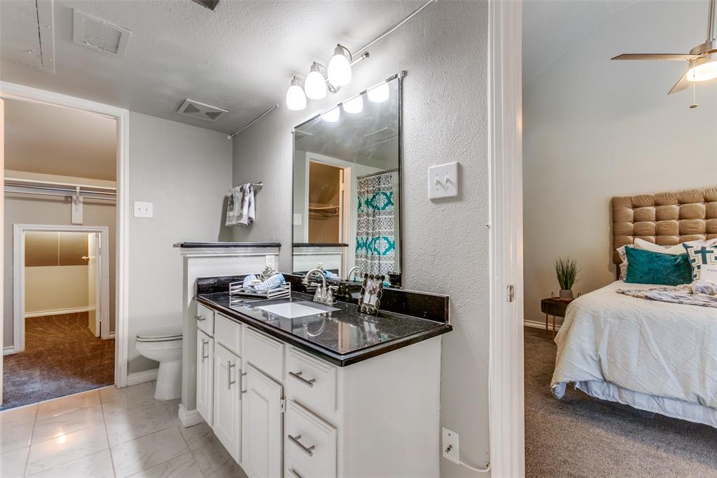 Bathroom vanity featuring white cabinetry, a dark stone countertop, an integrated rectangular sink, and a multi-bulb vanity light fixture