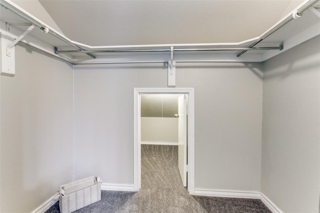 Walk-in closet featuring white wall-mounted shelving with integrated chrome garment rods and carpeted flooring