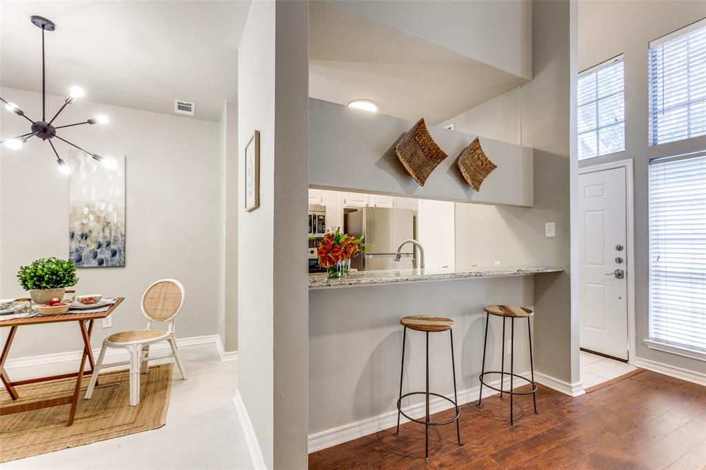Multi-level living area featuring a breakfast bar with stone-surfaced countertop, high ceilings, large grid-pane windows, and a modern sputnik-style chandelier