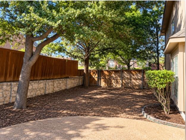 Side yard off of pool and patio- Backyard featuring wood privacy fencing, and mature trees.