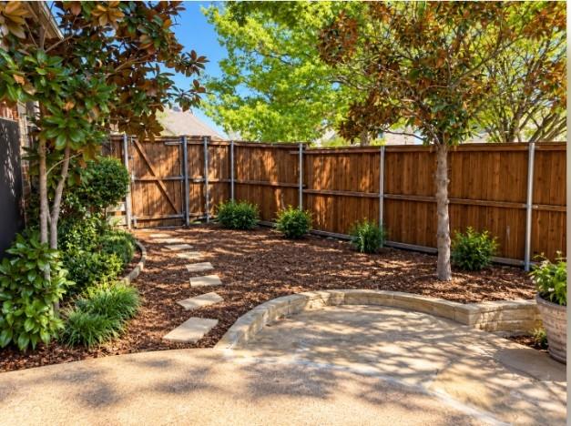 Backyard featuring a stone paver walk to Gate and driveway, wood privacy fencing, and mature trees.
