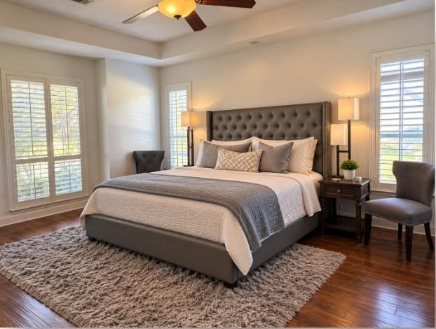 Tray ceiling with a central ceiling fan, hardwood flooring, and white plantation shutters