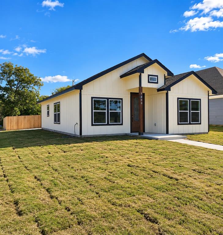 Single-story exterior featuring board-and-batten siding, contrasting dark window trim, a covered entry with wood-post detailing, and a fenced yard Single-story exterior featuring board-and-batten siding, contrasting dark window trim, a covered entry with wood-post detailing, and a fenced yard