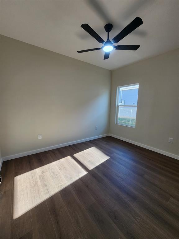 Room with wood-finish flooring, neutral wall paint, single-pane window, and a multi-blade ceiling fan with integrated lighting