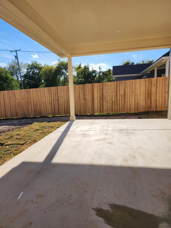 Covered concrete patio featuring a vertical wood privacy fence and structural support column