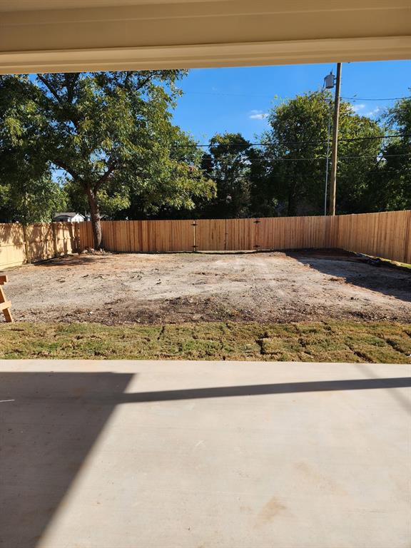 Concrete patio overlooking an enclosed backyard featuring a wood privacy fence and mature trees