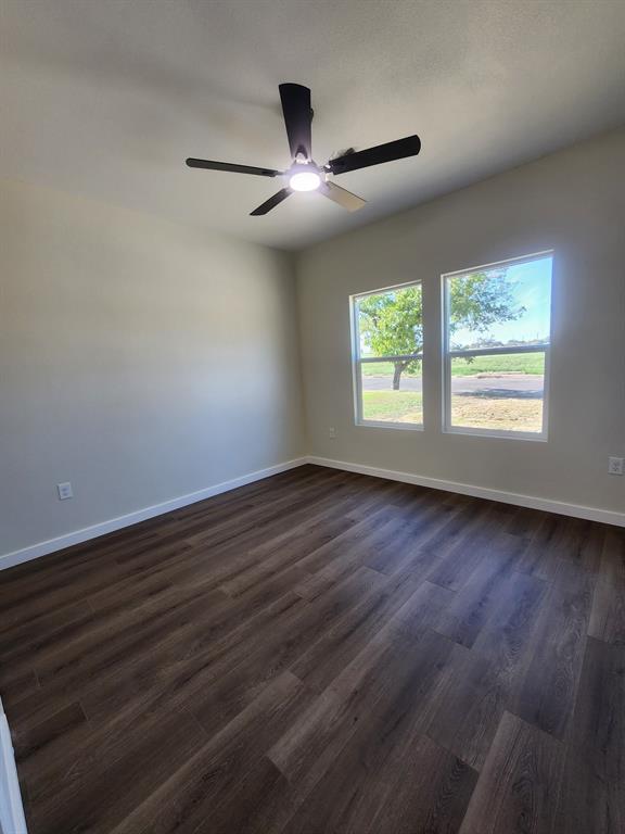 Interior space featuring wood-finish flooring, neutral wall paint, double-pane windows, and a matte black ceiling fan with an integrated light fixture Interior space featuring wood-finish flooring, neutral wall paint, double-pane windows, and a matte black ceiling fan with an integrated light fixture