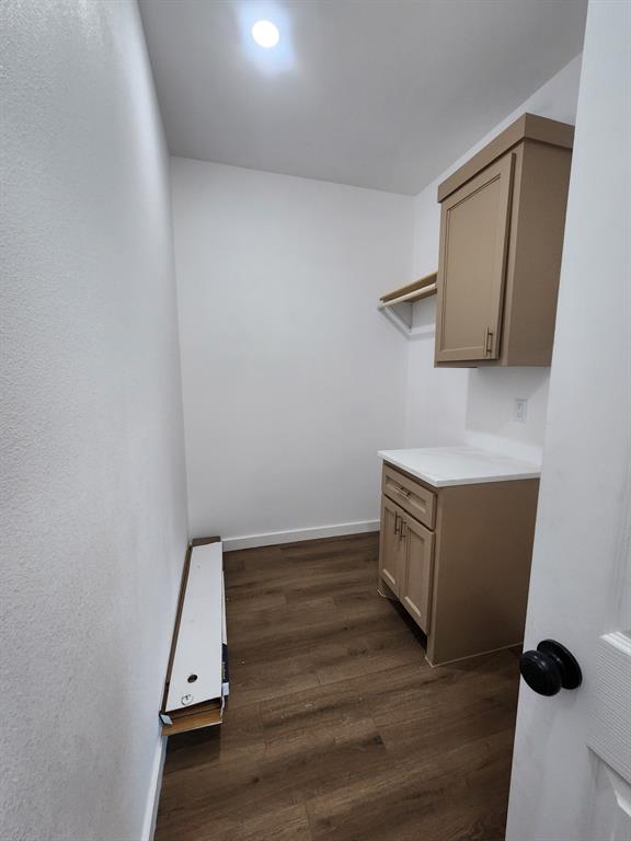 Utility space featuring wood-finish flooring, built-in cabinetry with light-toned surfaces, a countertop, and recessed ceiling lighting