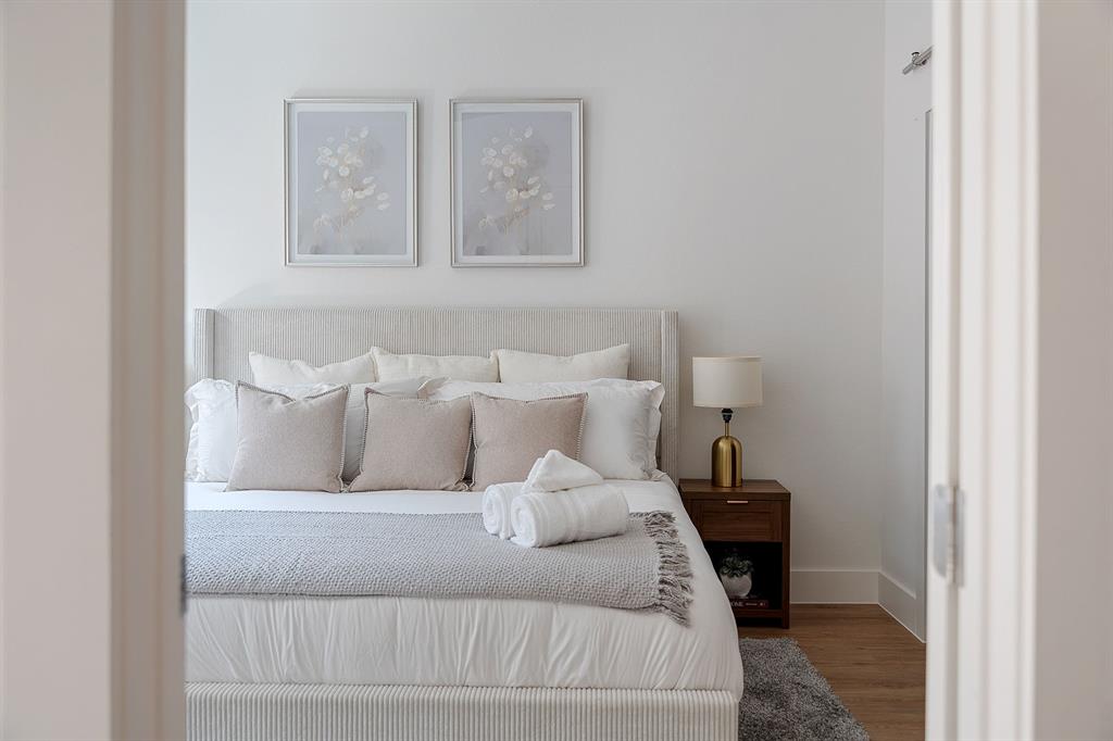 Neutral-toned bedroom featuring wood-finish flooring and a minimalist aesthetic