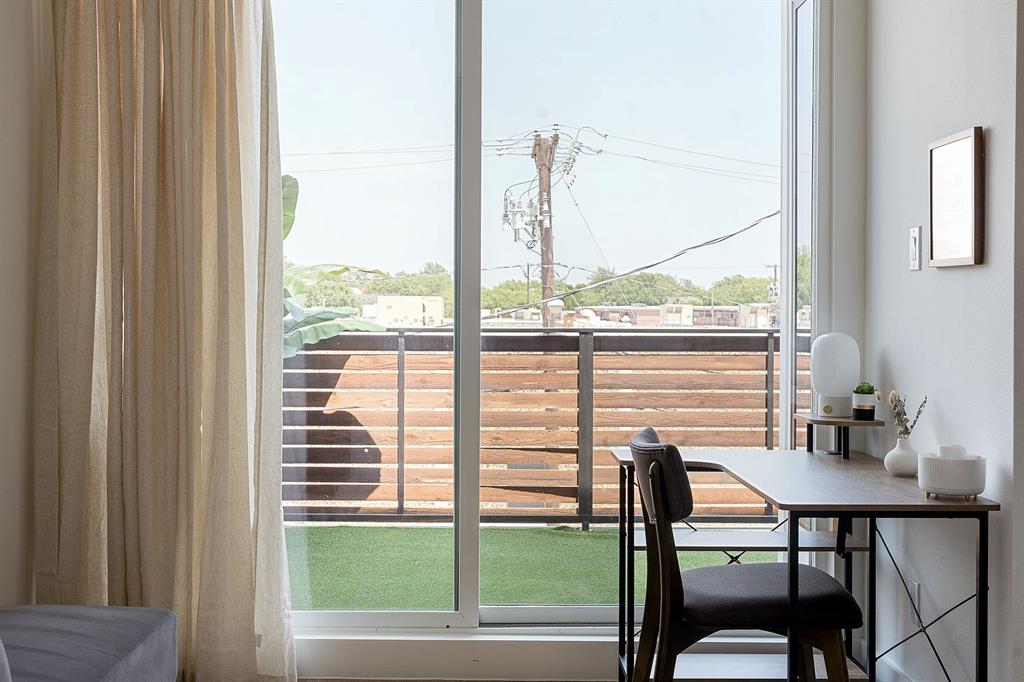 Floor-to-ceiling glass sliding door, balcony with horizontal wood-slat privacy railing, and synthetic turf flooring