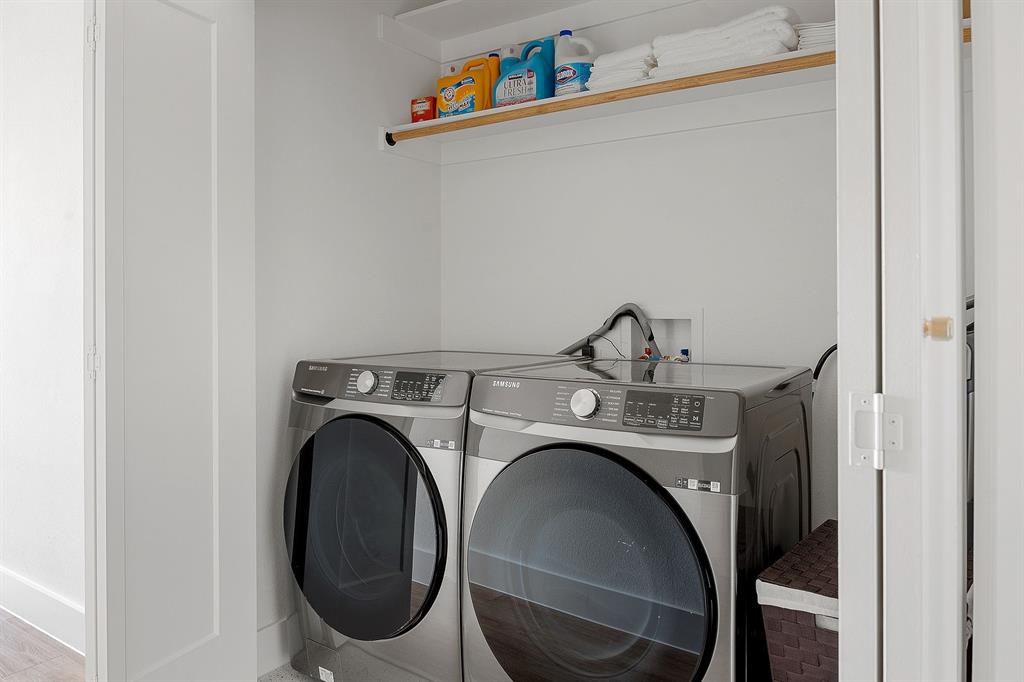Laundry alcove featuring stainless steel front-load appliances and overhead built-in shelving