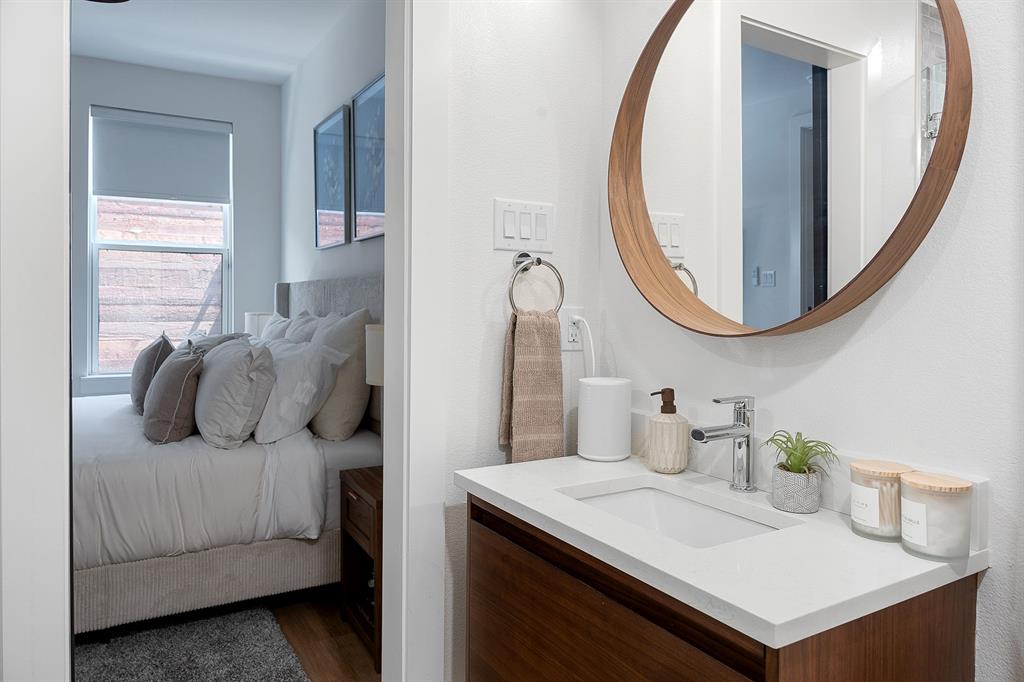 Wall-mounted circular wood-finish mirror, vanity with white countertop and integrated sink, and polished chrome faucet