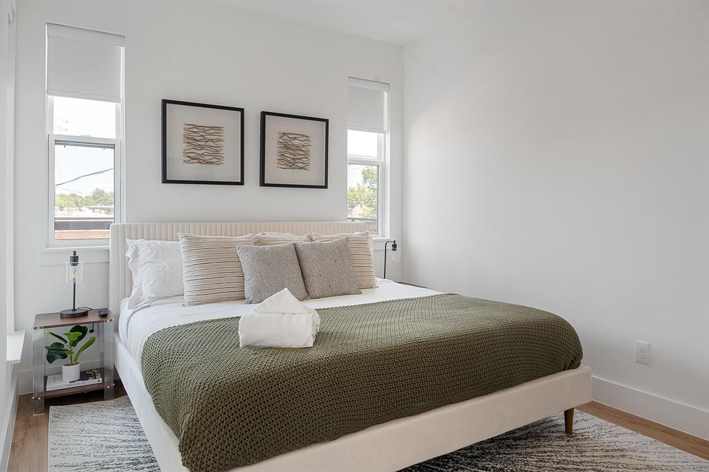 Room featuring white walls, wood-finish flooring, and dual windows with fitted shades