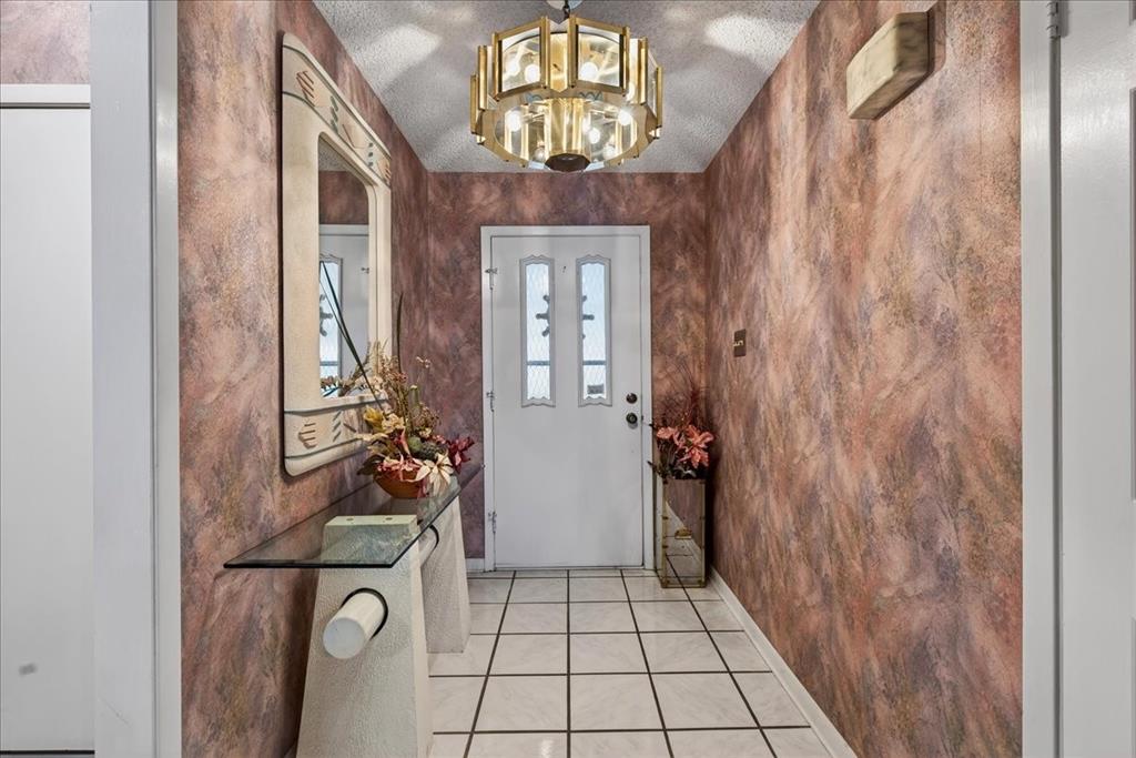 Entryway featuring tile flooring, textured wall finishes, and a tiered metallic chandelier