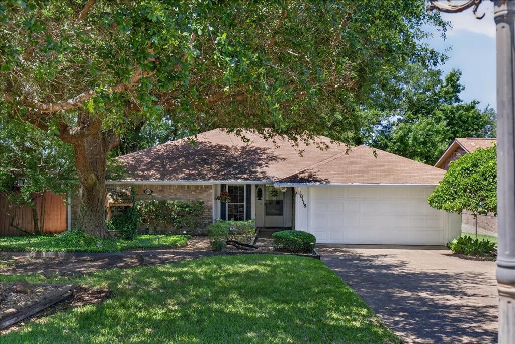 Single-story residence featuring a brick and siding exterior, multi-pitched shingle roof, attached two-car garage, and mature landscaping