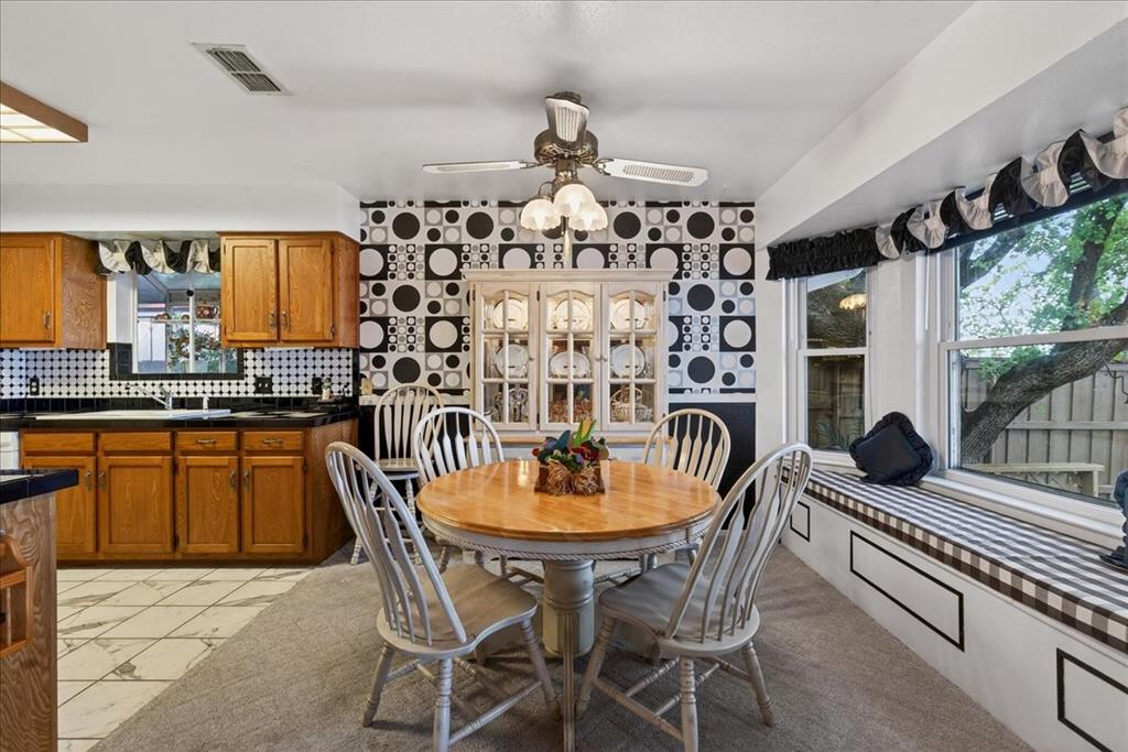 Dining area featuring a built-in china cabinet, window seat, ceiling fan with integrated lighting, and tile flooring
