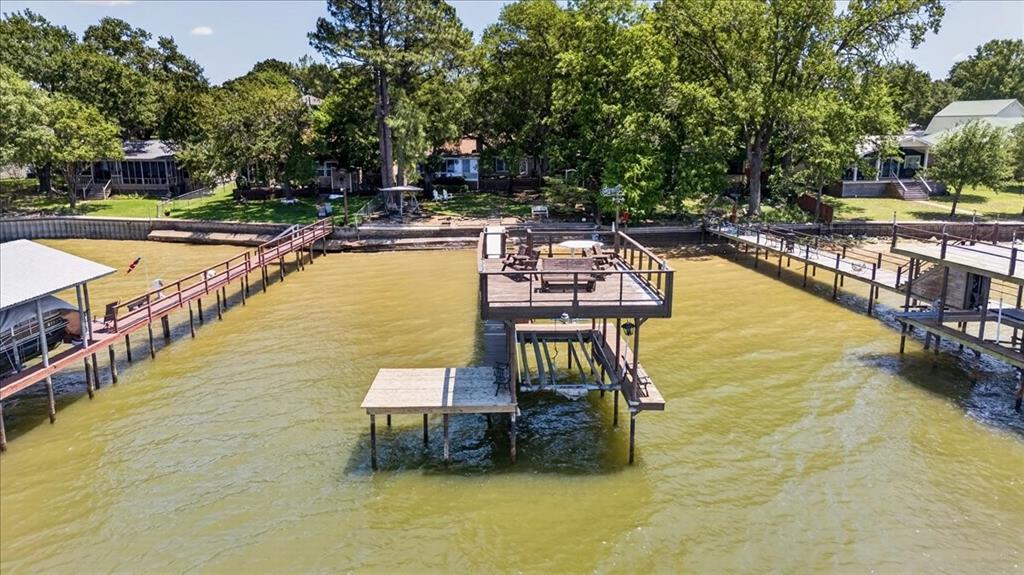 Waterfront property featuring a dual-level wood dock, covered boat slip, steel bulkhead, and elevated deck platform with railing